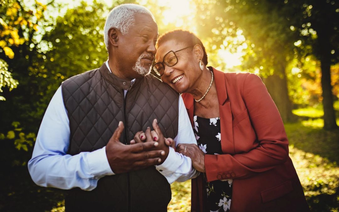 Preferred Insurance Colorado - Medicare - Medicare Advantage vs Medigap - older man and woman walking arms linked smiling down park path